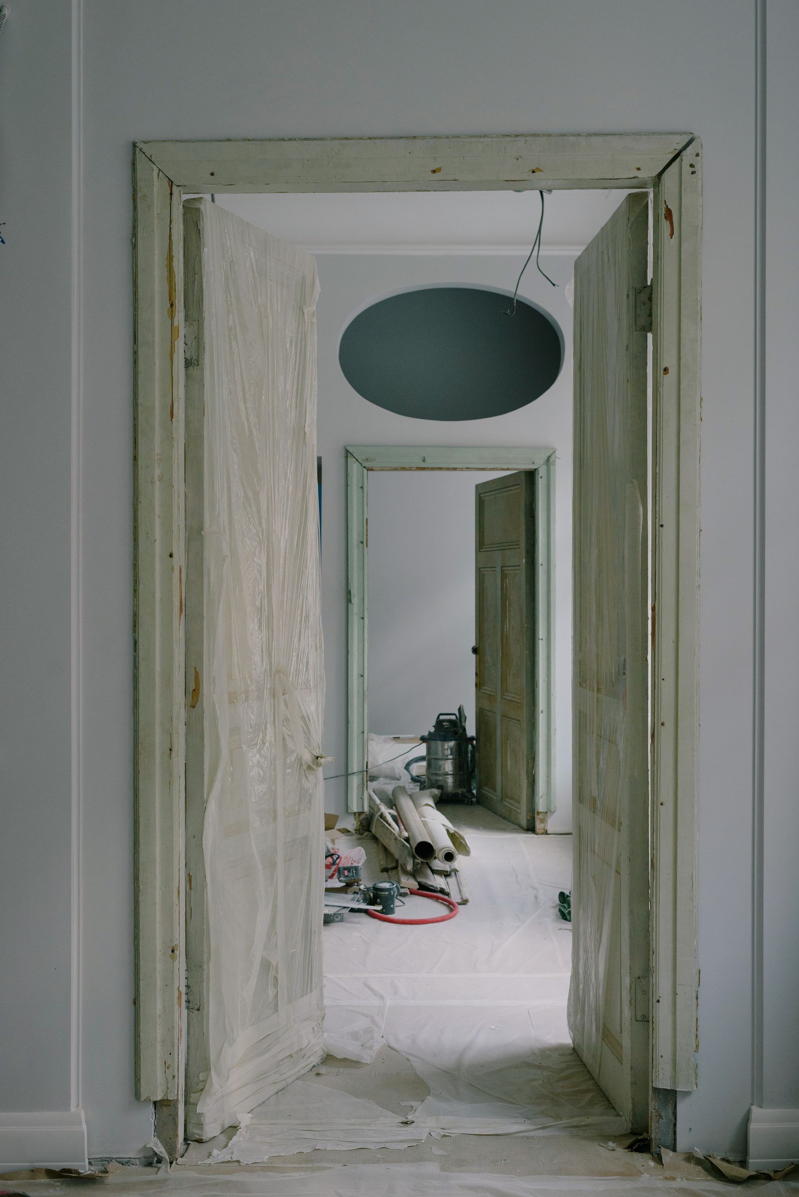 Puertas abiertas de una vivienda en reforma, con plásticos en el suelo y herramientas al fondo.