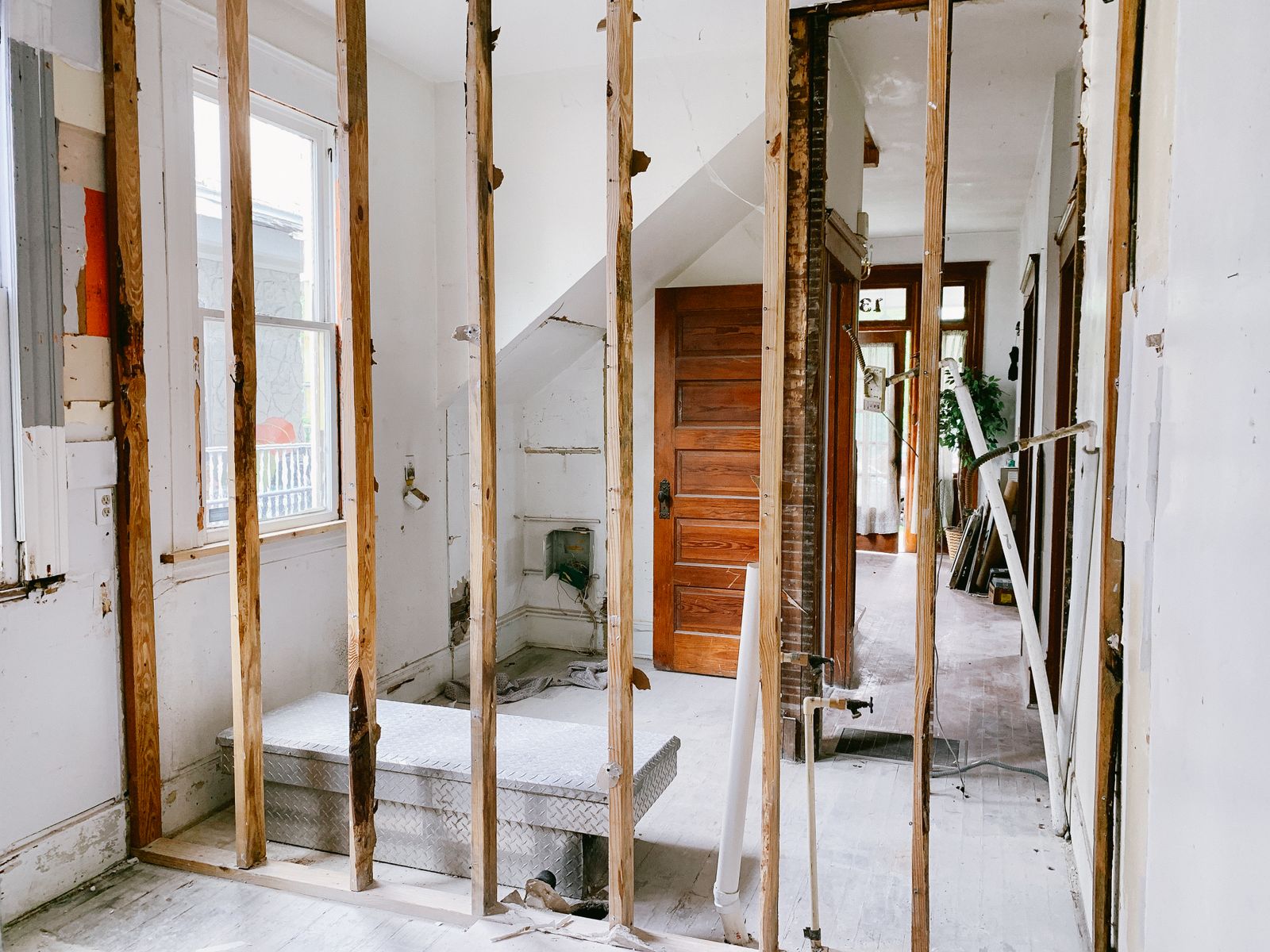 Estancia de una casa en obra, con montantes de madera a la vista y una puerta al fondo.